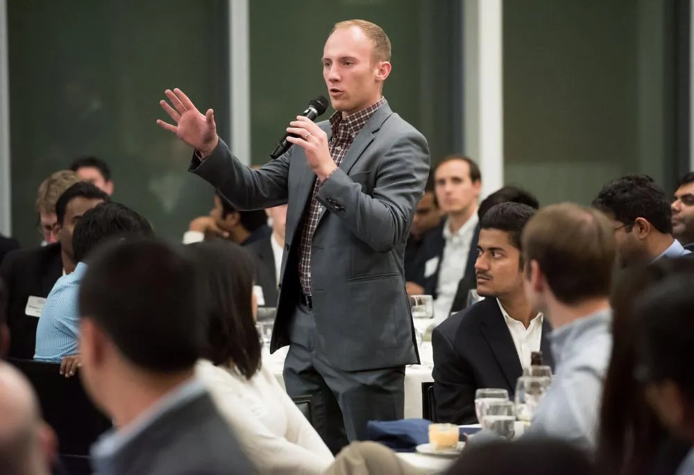 A student in a suit speaking at a Global Operations Conference