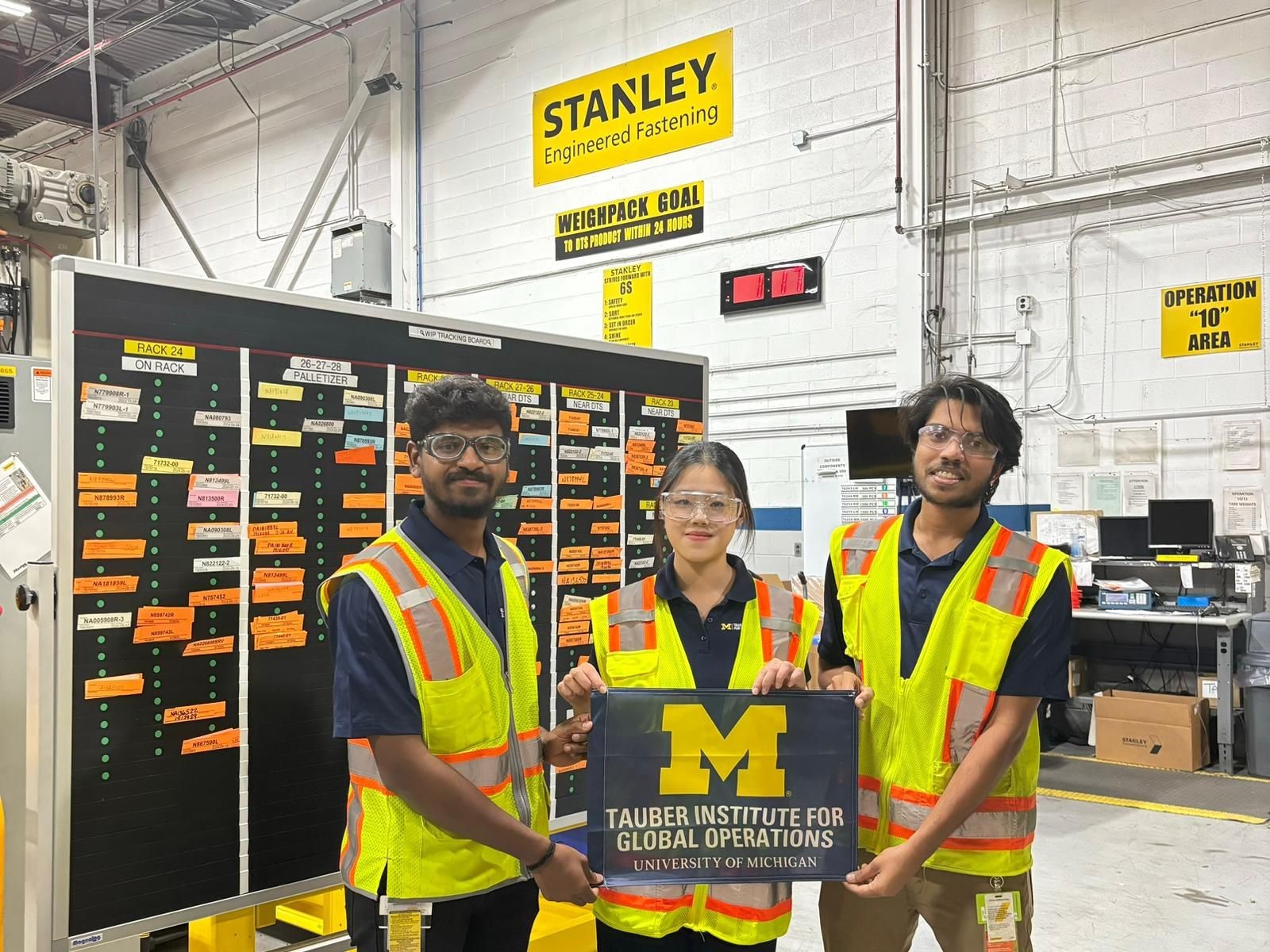 Students from Stanley Black and Decker posing in their warehouse with the Tauber Flag