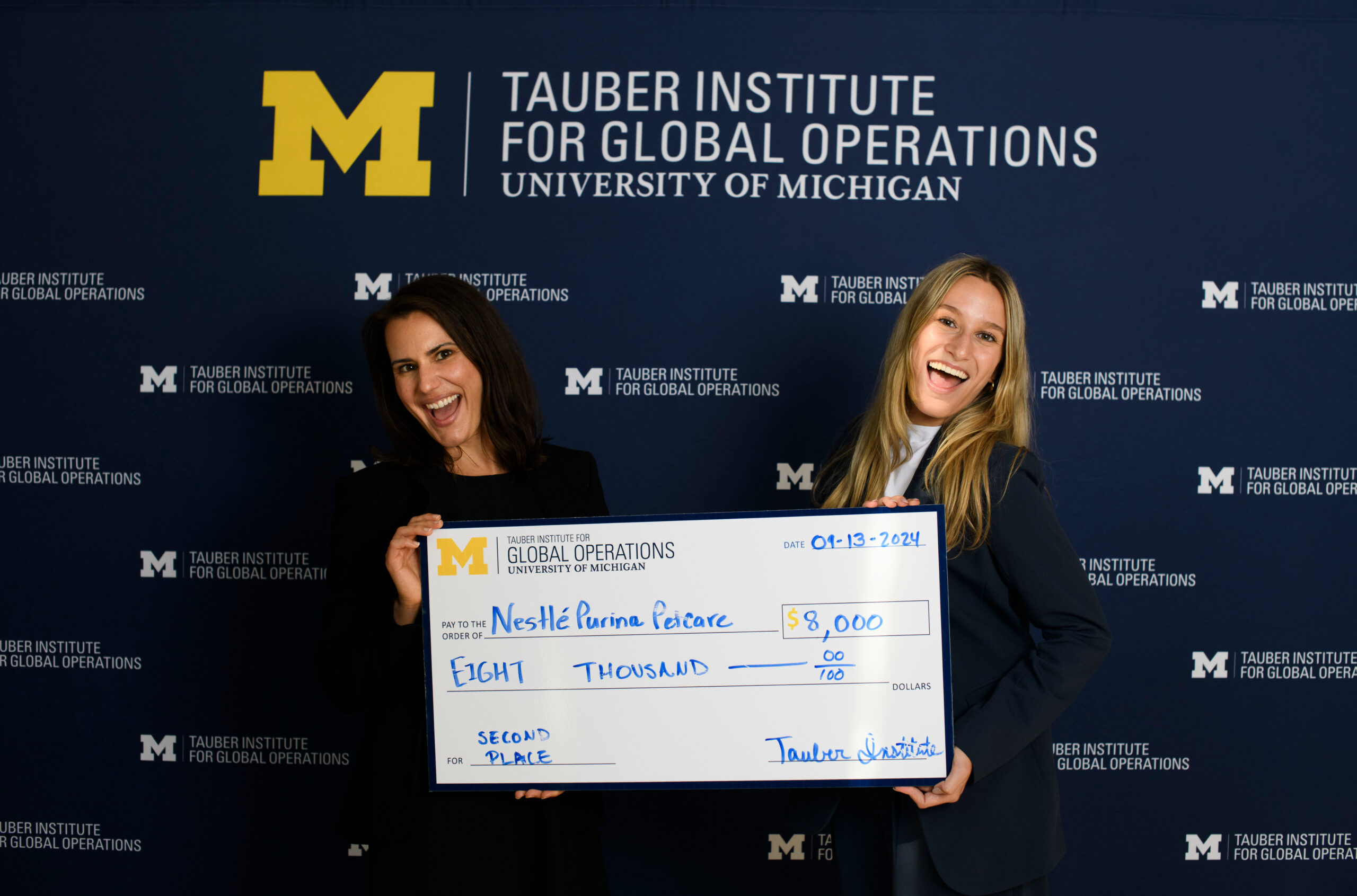 students pose with a giant scholarship check