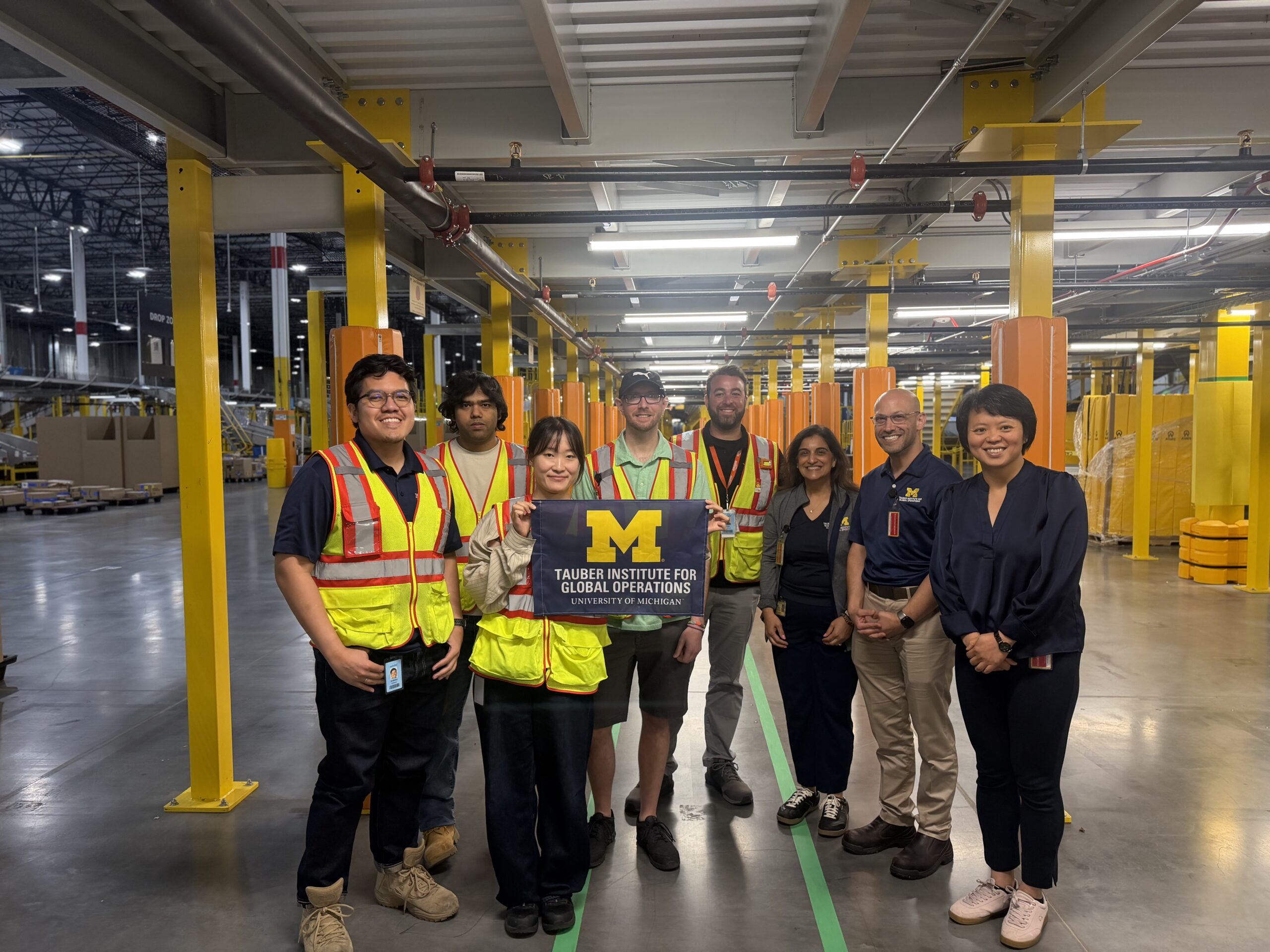 A group poses in a warehouse holding the Tauber flag.