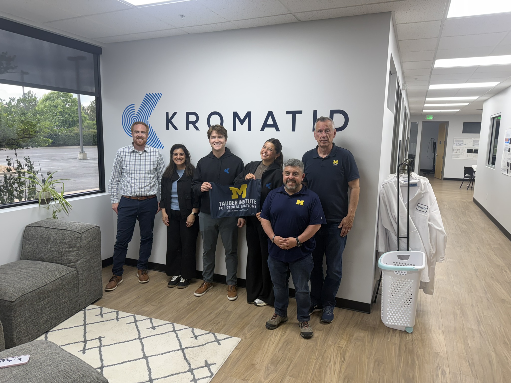 A group of people pose in front of the Kromatid logo