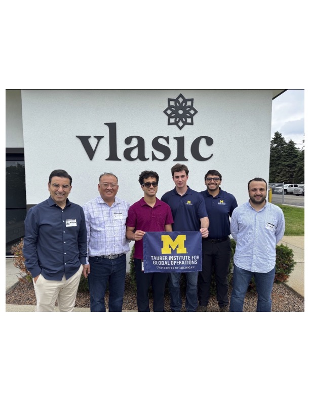 A group of people pose with the Tauber flag in front of Vlasic building