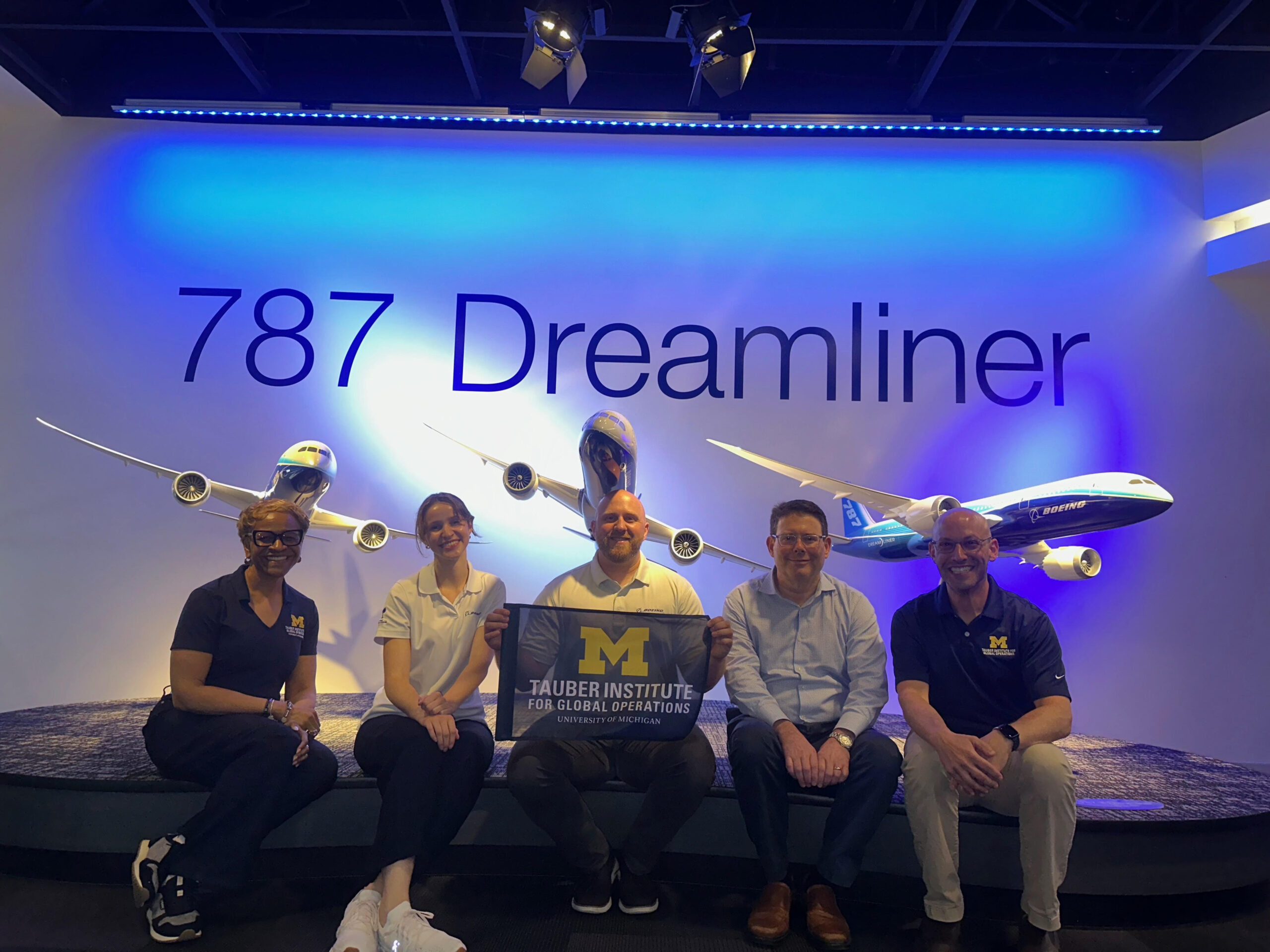A group of people sit in front of Boeing's 787 Dreamliner display