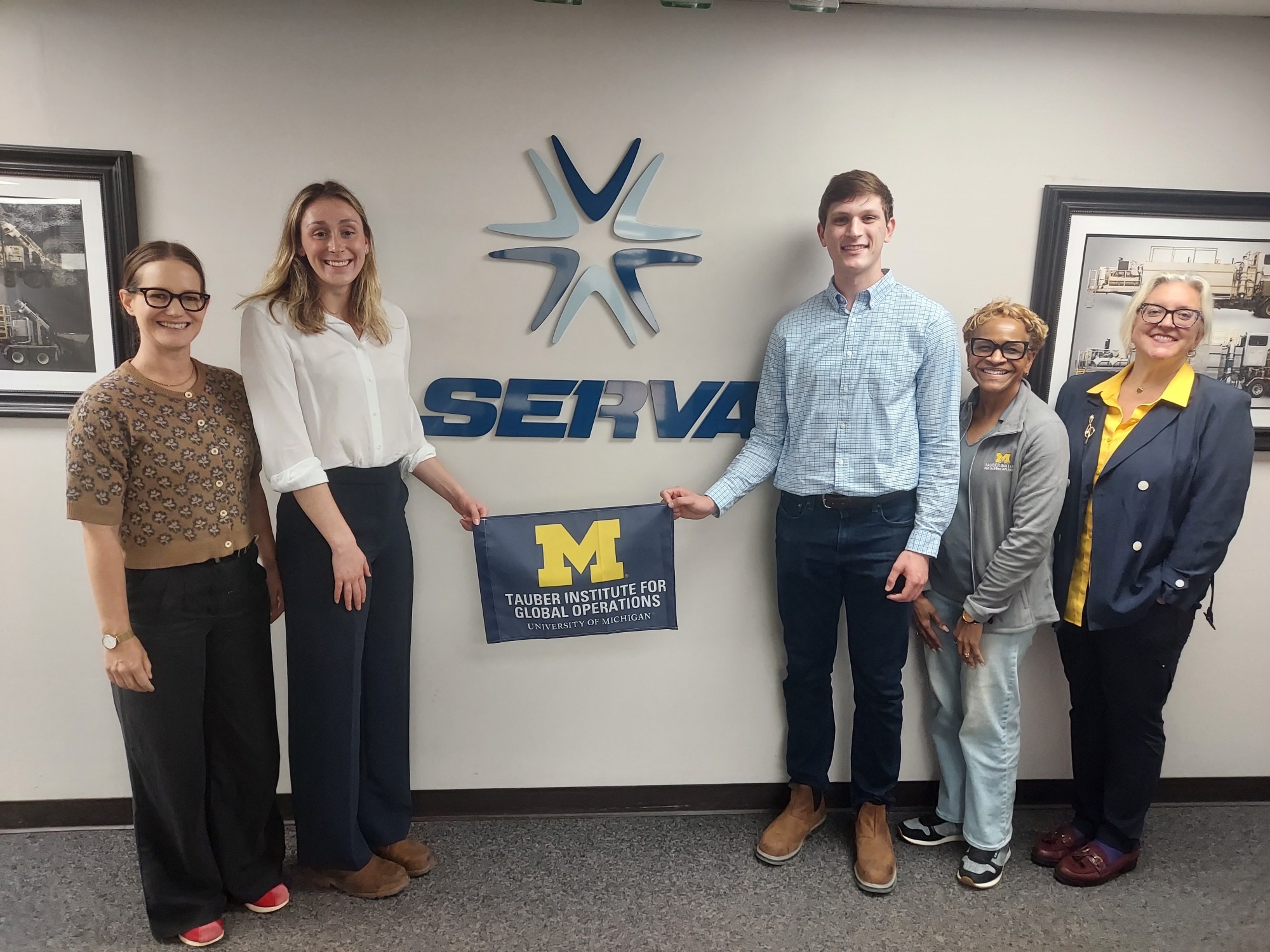 A group of people hold the Tauber flag in front of the Serva logo