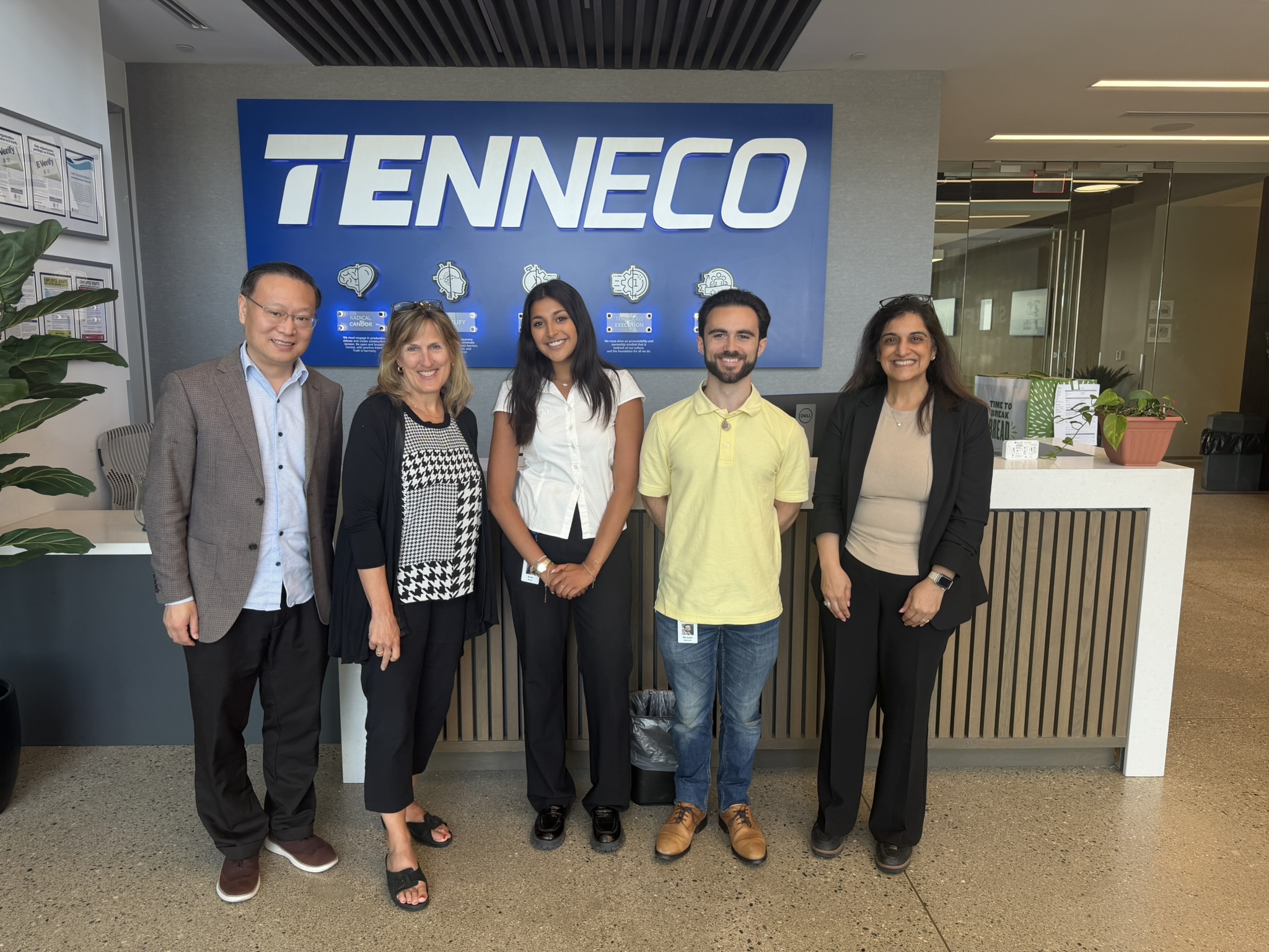 A group of people pose in front of the Tenneco logo